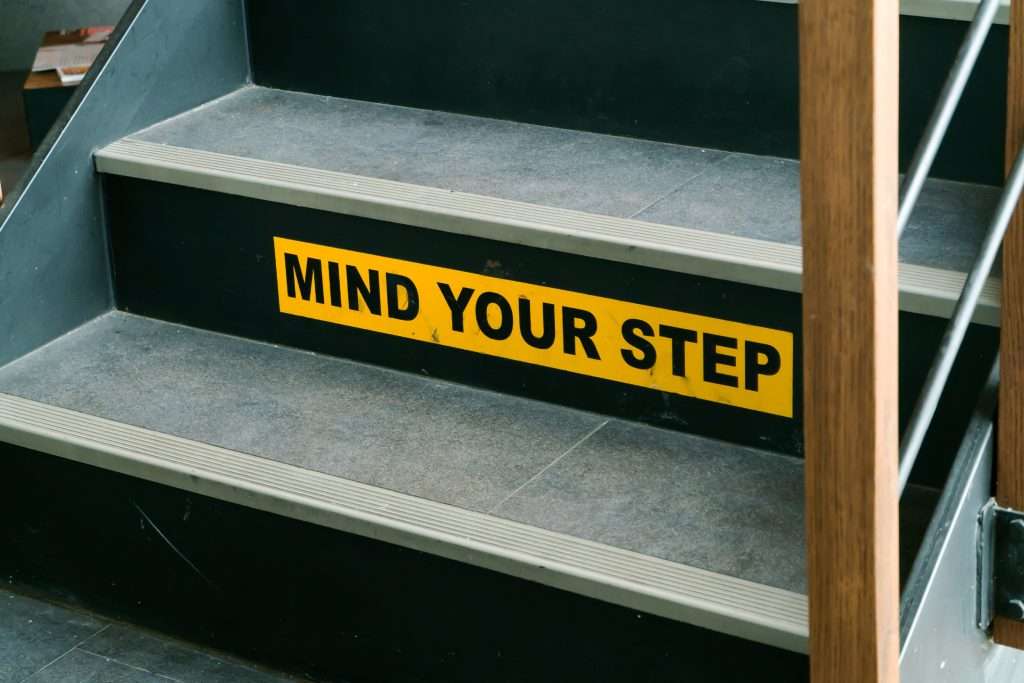 Stairs with a cautionary "mind your step" sign to remind people to be careful while walking up or down.